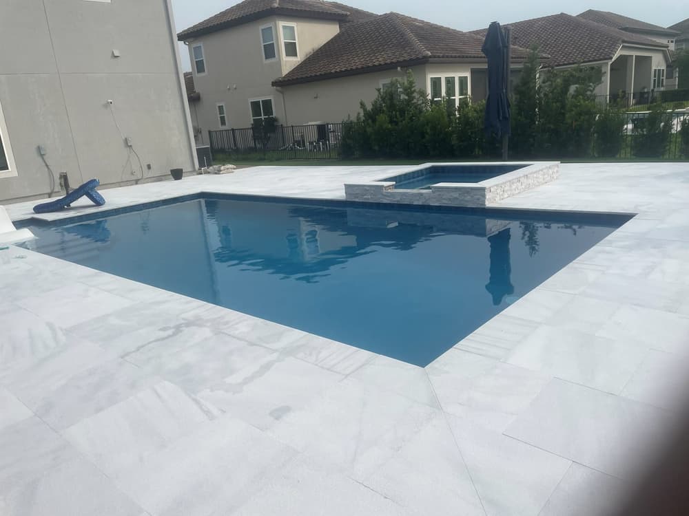 Rectangular pool with a raised spa, Glass tile spillway, white paver deck