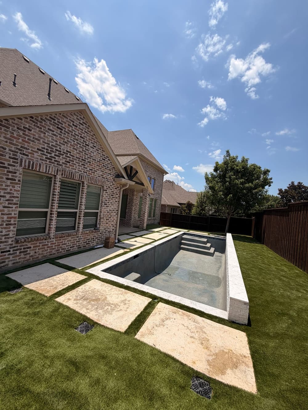 Plunge pool with raised beam, Stacked stone, turf and travertine pads