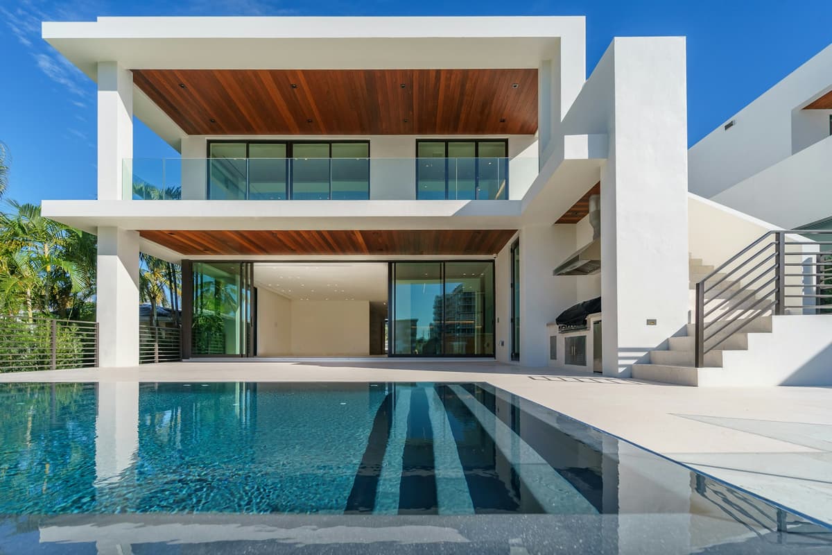Modern rectangular pool beside a two-story home with a covered patio